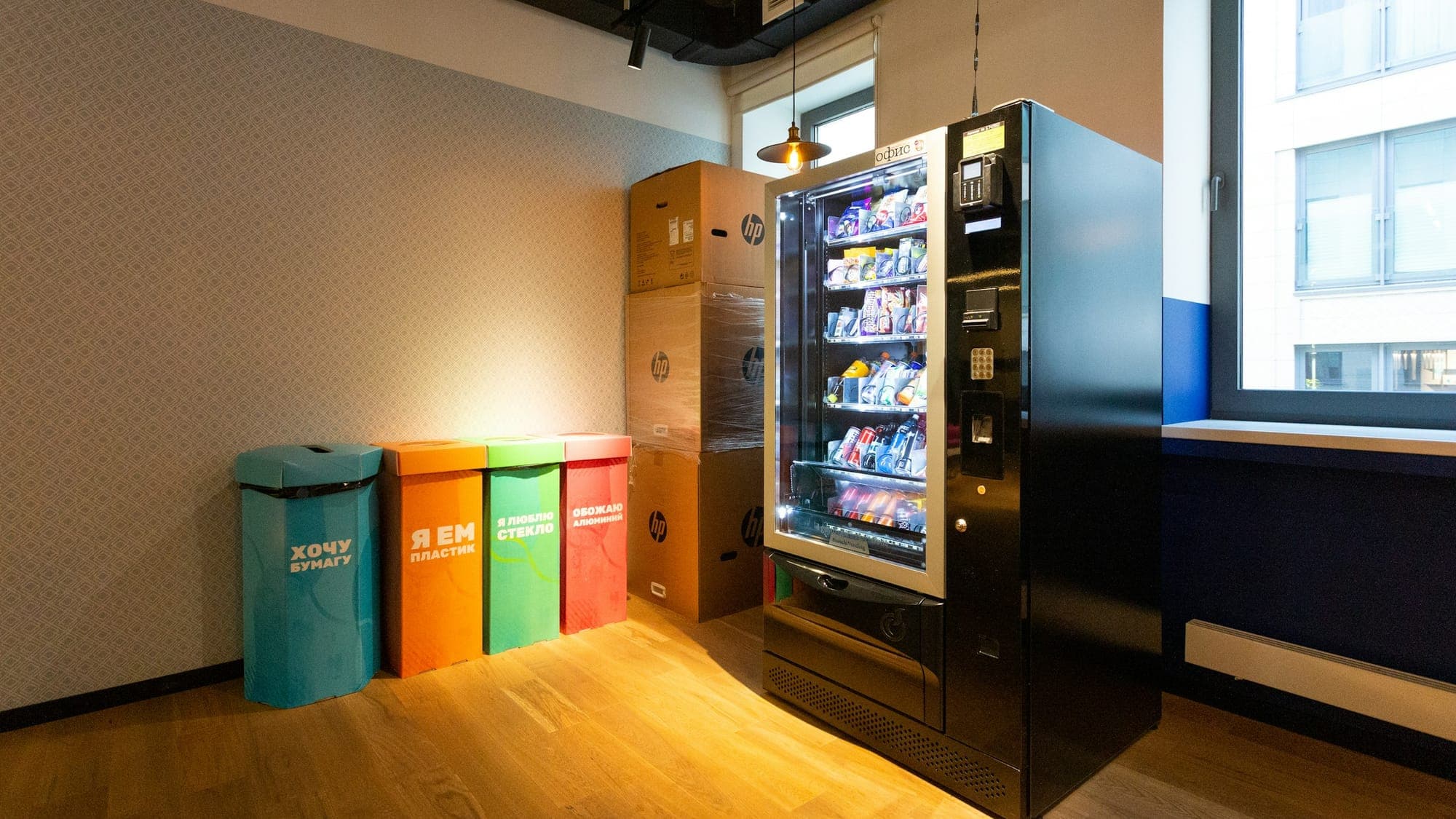 Office corner with a vending machine and coloured waste bins