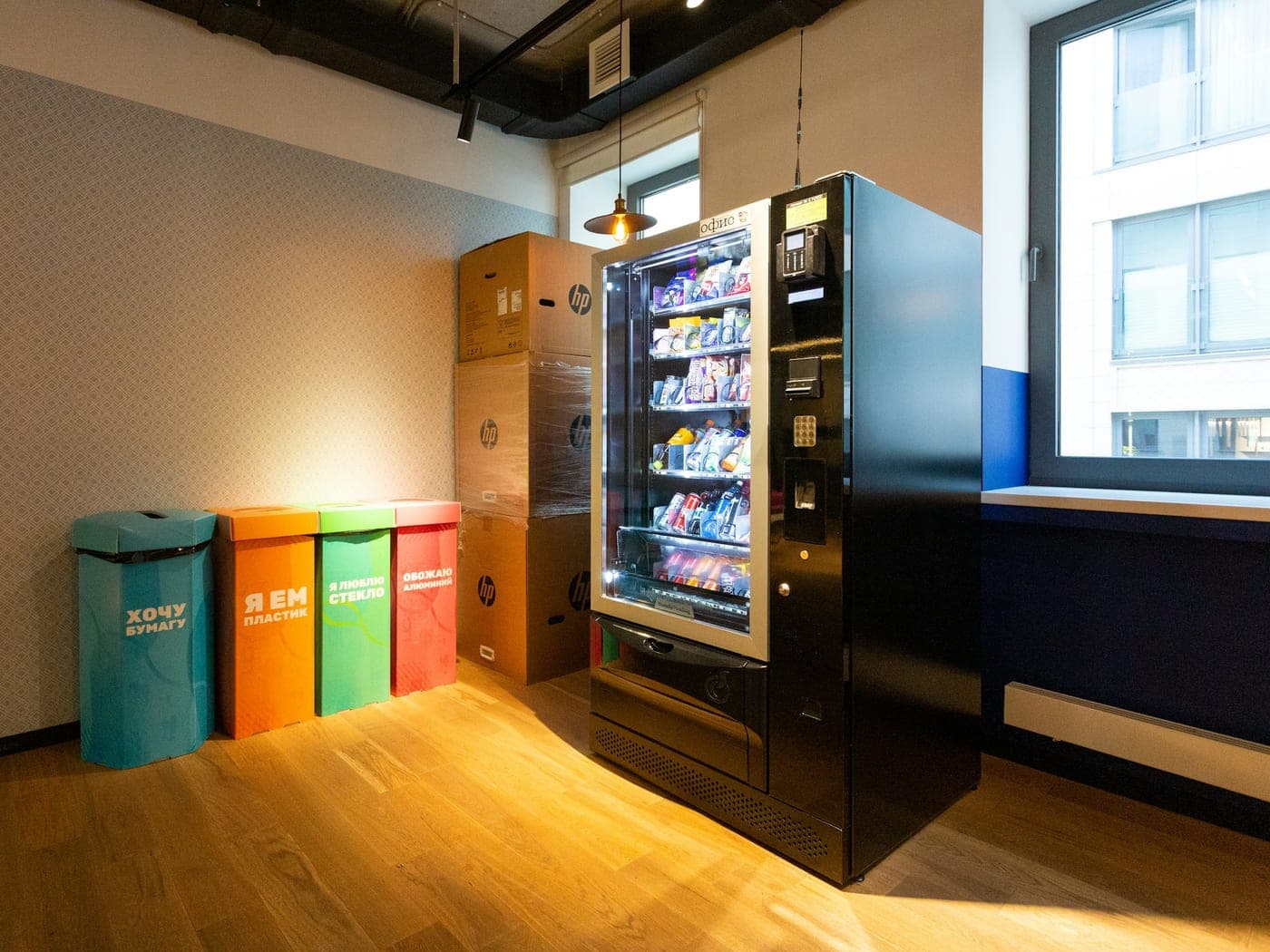 Office corner with a vending machine and coloured waste bins