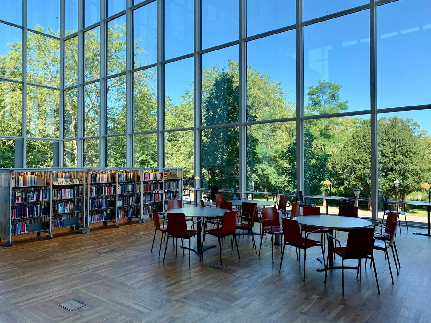 Bright school library with tall windows, bookcases and red chairs