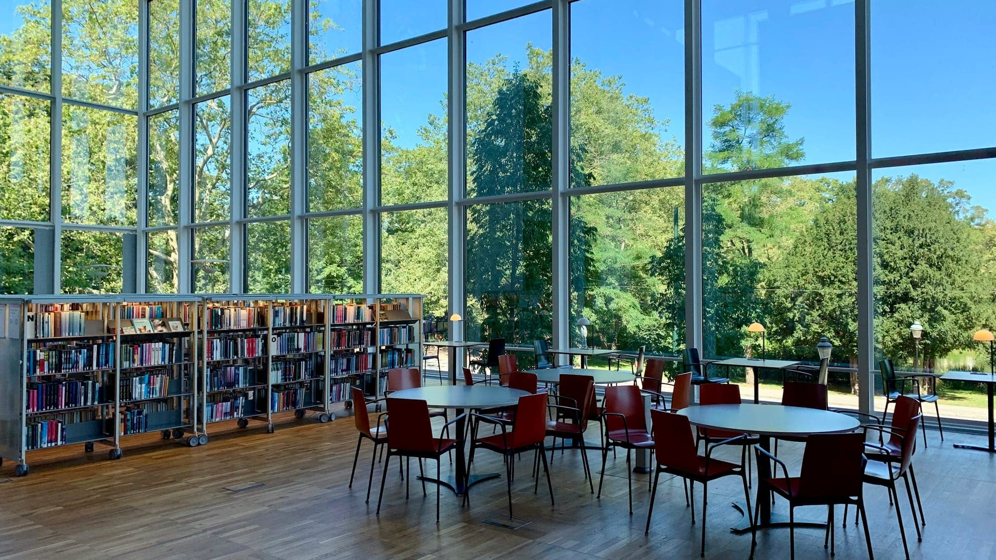 Bright school library with tall windows, bookcases and red chairs